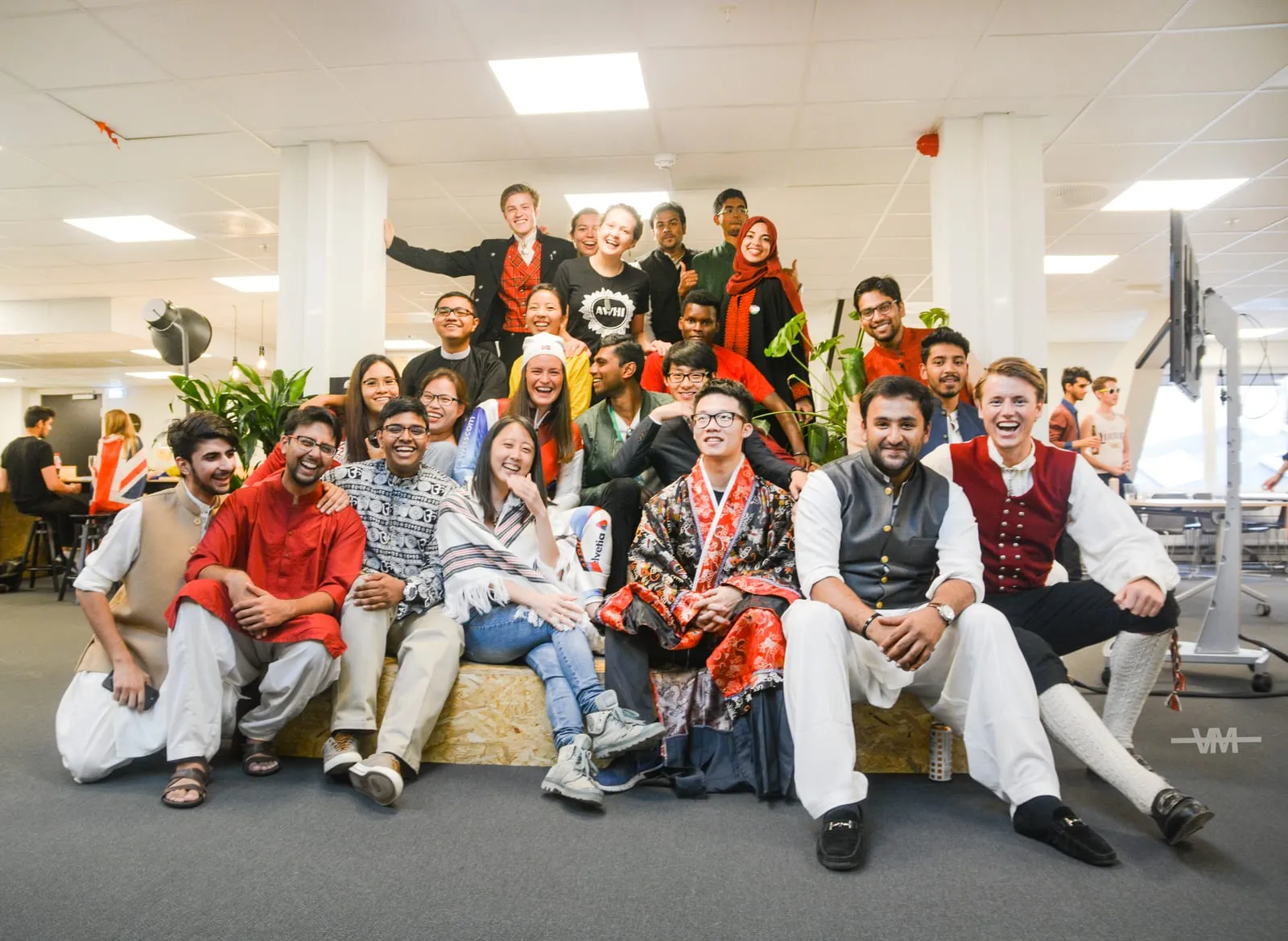 A big group in national costumes from everywhere, posing in an office
