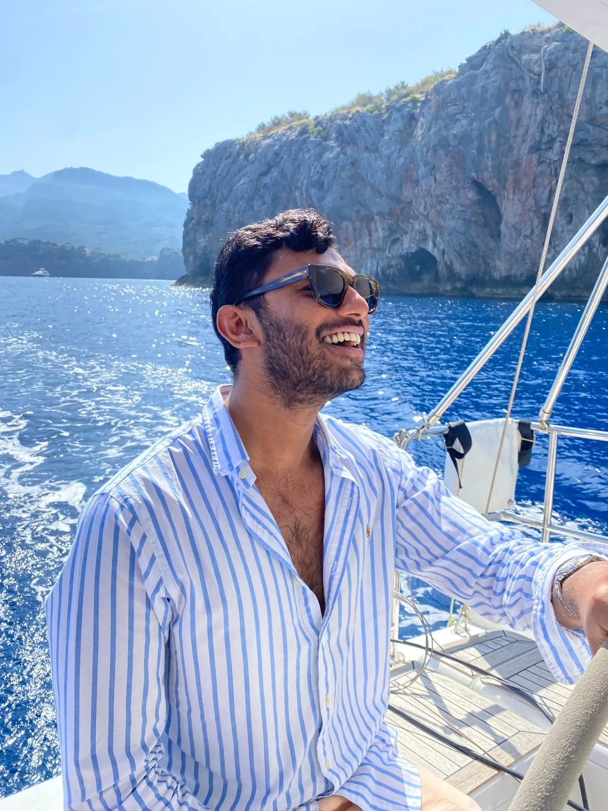 Laughing on a sailboat, cliffs behind