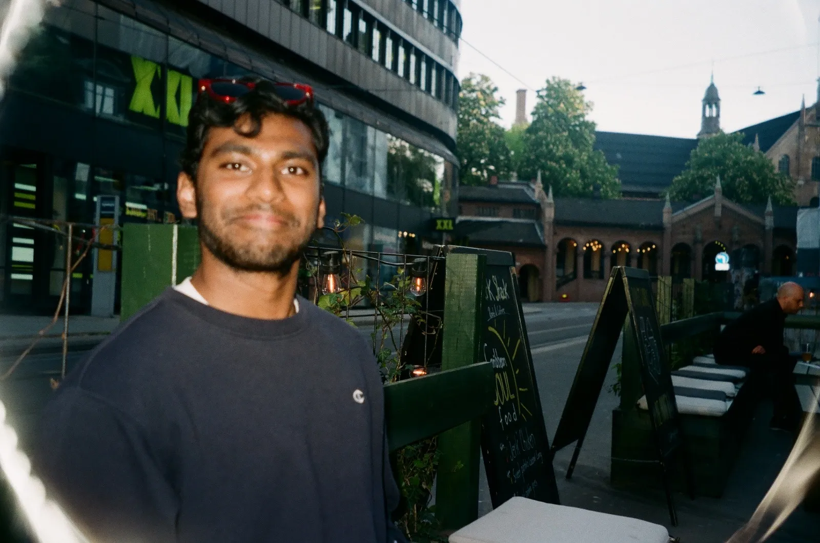 Me outside a street café on film, sunglasses on my head